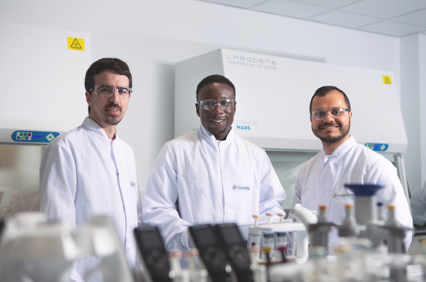 Scientists in a laboratory conducting mycoplasma testing with specialized equipment in the background.