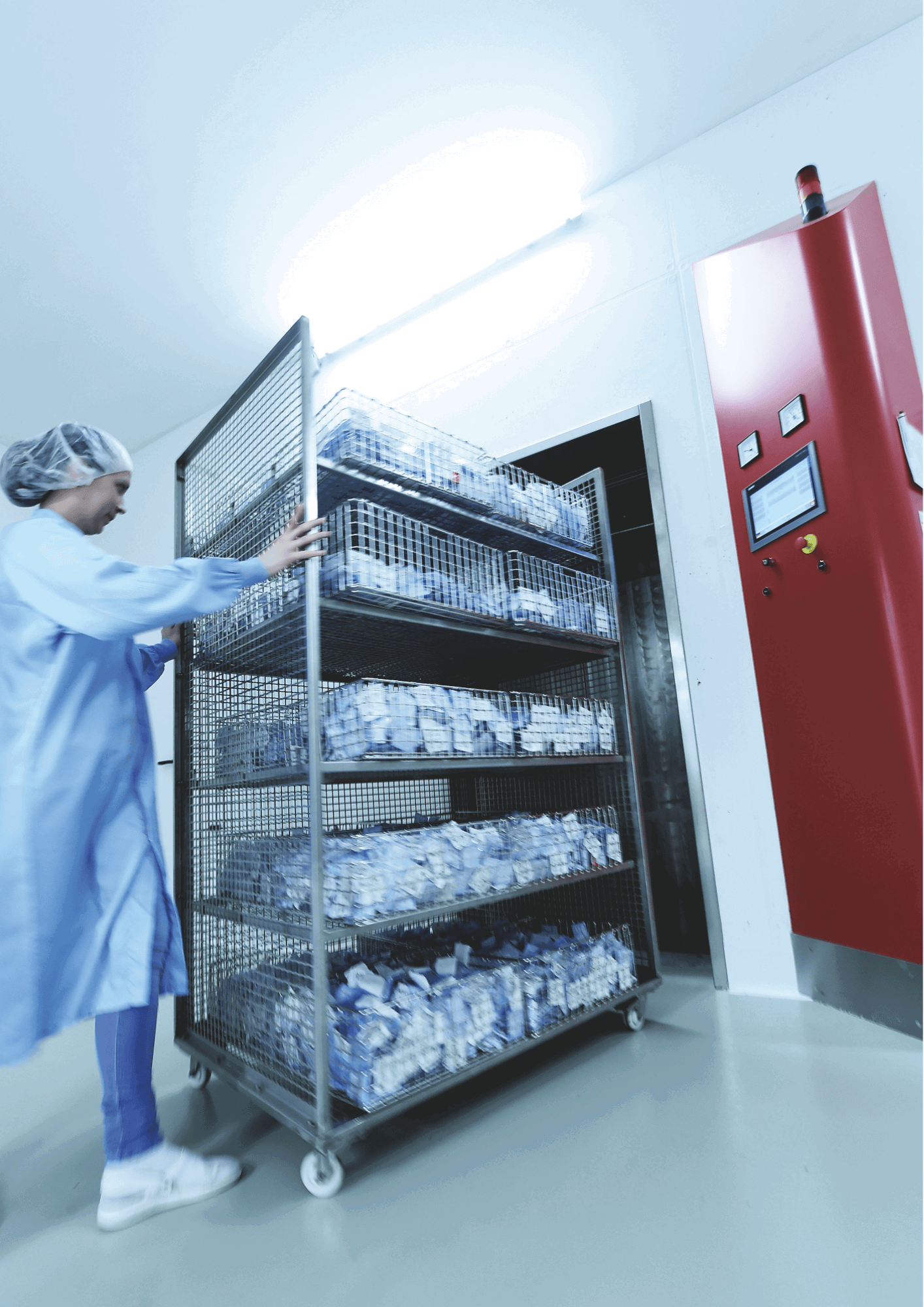Technician moving a cart into EO steriliser chamber for medical device sterilisation.