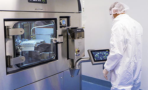 Scientist in a white lab coat performing Sterile Fill and Finish in a controlled laboratory environment, using the Vanrx Microcell™ Vial Filler.