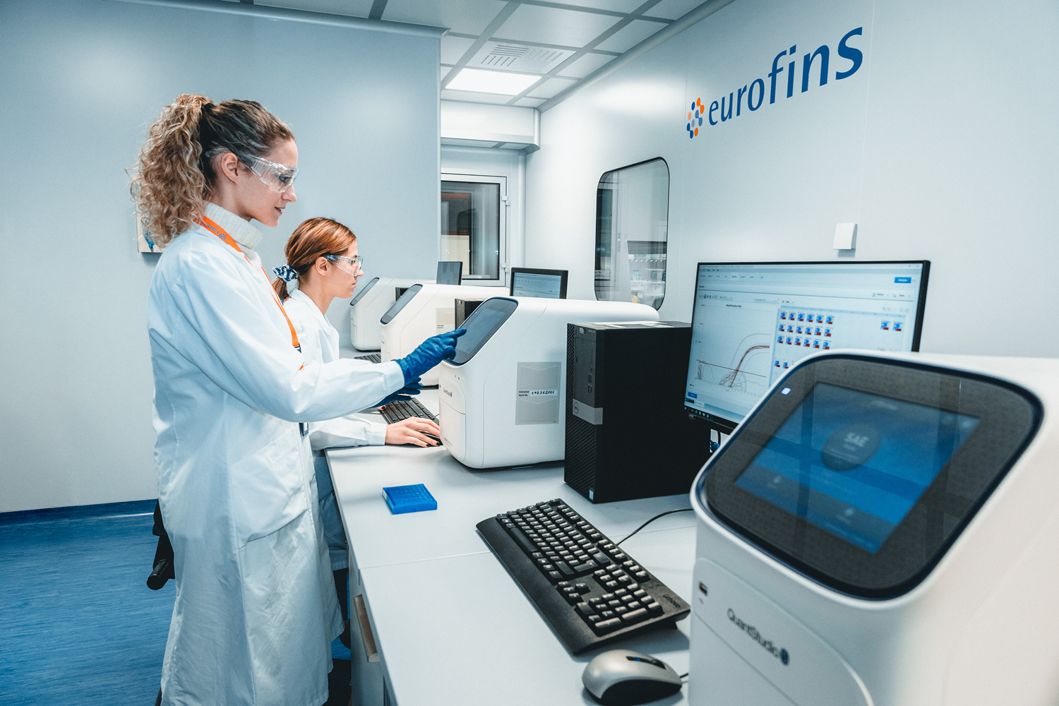 Lab technicians analysing data on monitors from mycoplasma testing samples with advanced real time PCR equipment.