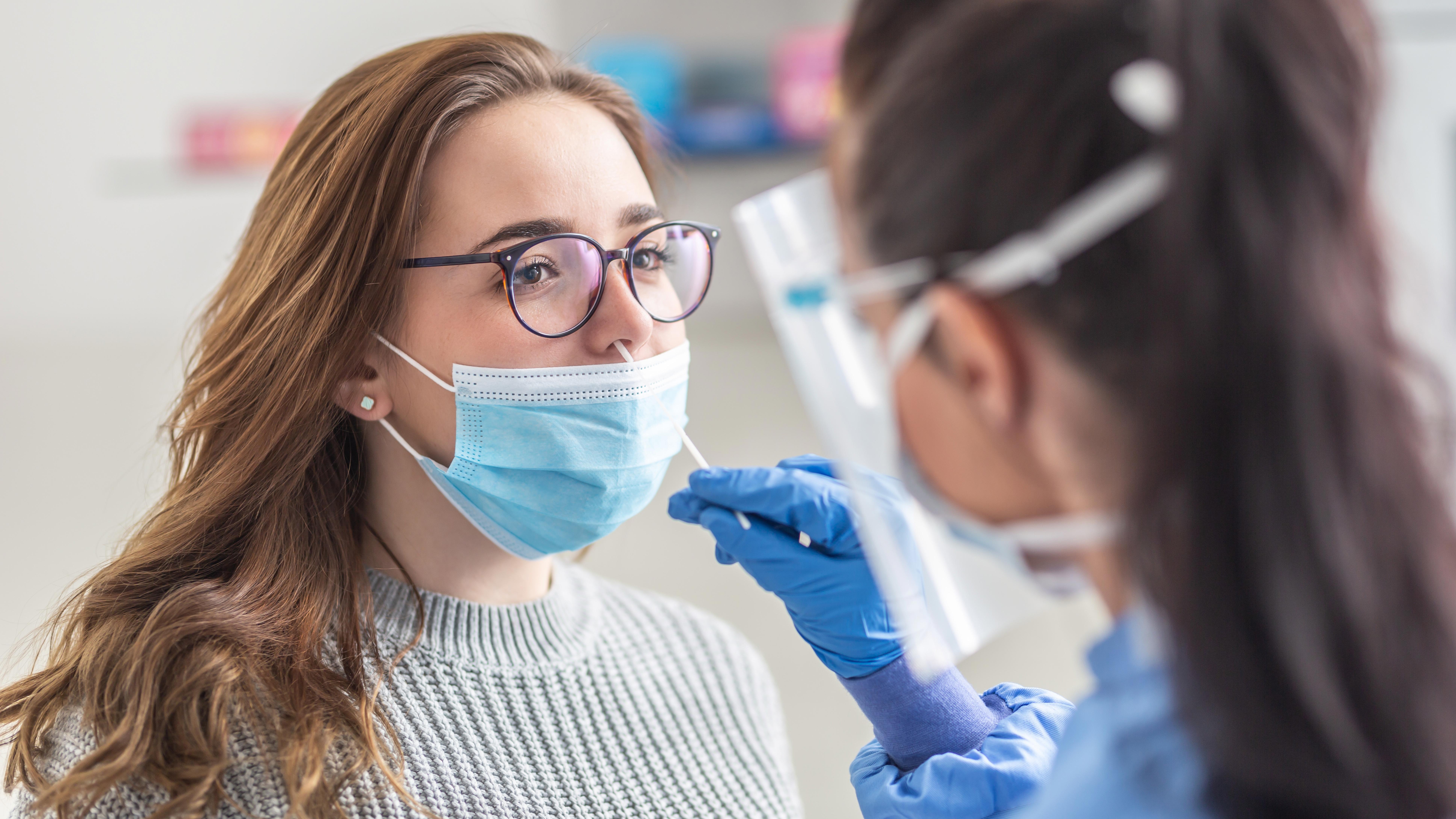 female-patient-wearing-mask-over-mouth-is-having-sample-taken-from-nose-for-a-pcr-test-for-covid-19_cropped-169