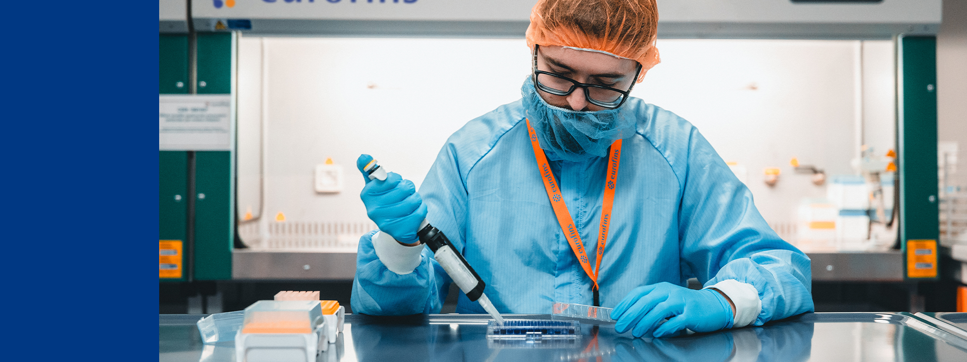 Laboratory setting with a technician wearing protective clothing and gloves, using a pipette to transfer liquid into a container. The background features the 'eurofins' logo and various laboratory equipment. This environment is focused on analytical chemistry and the study of physicochemical properties, which involves analyzing the chemical composition and physical characteristics of substances to ensure their quality, stability, and efficacy in pharmaceutical development.