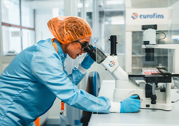 Scientist performing microscopy analysis in a controlled laboratory environment to assess antibiotic potency as part of Eurofins BioPharma Product Testing services.