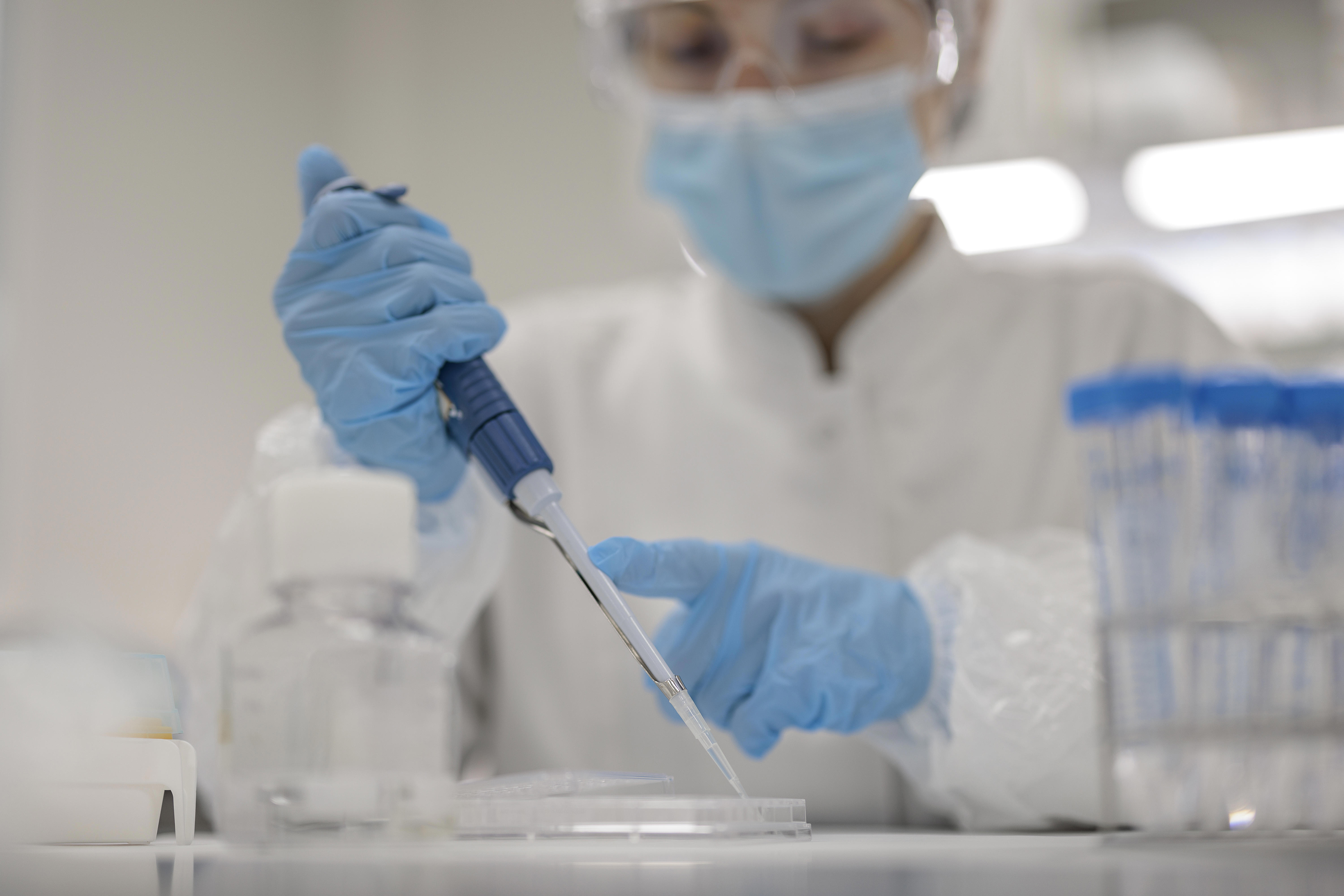 In a sterile product testing lab, a scientist in protective gear carefully transfers liquid with a pipette for endotoxin testing