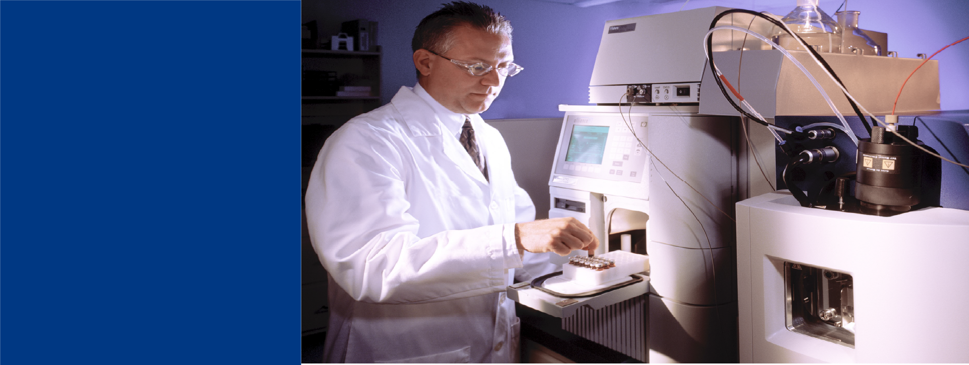 Scientist in a white lab coat operating an analytical instrument in a laboratory, performing process residuals testing.