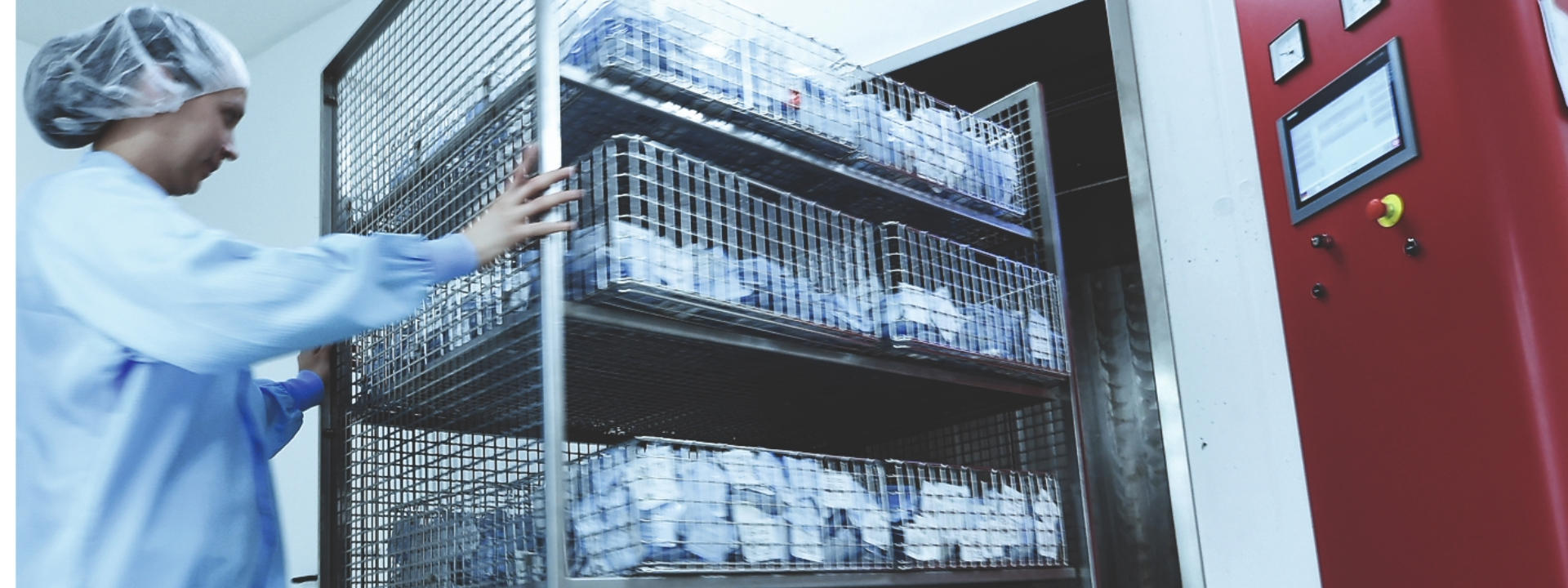 Technician moving a cart into EO steriliser chamber for medical device sterilisation.
