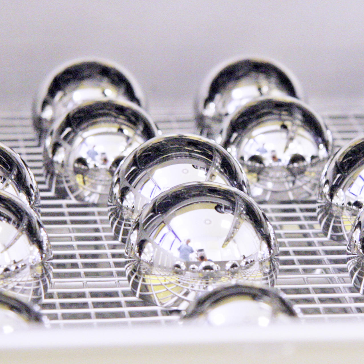 Several reflective, metallic spheres arranged in rows on a grid-like surface, reflecting surrounding lights and objects. The image is labeled 'Imaging'.